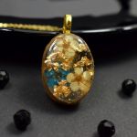 Owalny wisiorek z żywicy z kwiatuszkami i złotymi płatkami - naszyjnik kwiaty w żywicy