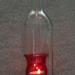 Świecznik z butelki z czerwonym kwiatem