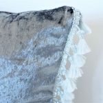 Welurowa szara poduszka z frędzlami - zbliżenie na tkaninę oraz dekoracyjne chwosty