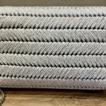 Makramowa torebka damska na ramię do eleganckich stylizacji - Zbliżenie na białą torebkę, prezentującą teksturowaną powierzchnię w jodełkę, metalowy zamek oraz łańcuszek.