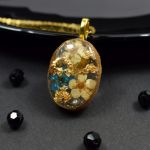 Owalny wisiorek z żywicy z kwiatuszkami i złotymi płatkami - naszyjnik kwiaty w żywicy