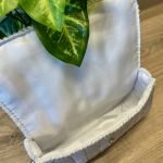 Torebka pleciona w jodełkę w kolorze białym z srebrnym akcentem - Jasna, estetyczna podszewka i wygodne zapięcie na zatrzask.