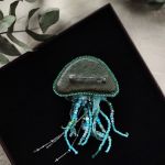 Broszka Meduza ręcznie haftowana, Broszka 3D, Unikatowy prezent dla kobiet - Wymiary: całkowita długość z mackami - 12cm, wymiary głowy: 4x6 cm - Broszka ma solidne zapięcie (typu agrafka) z obrotowym zabezpieczeniem, które zapobiega jej zgubieniu. Kolor srebrny. - Tył broszki wykonany jest z ciemnej zielonej skóry ekologicznej.