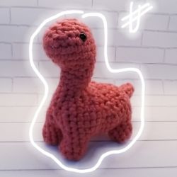 Koralowy dinozaur zrobiony na szydełku. Maskotka, zabawka.