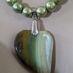 Naszyjnik składający się z dwóch sznurów z wisiorem z zielonym agatem w kształcie serca i szklanymi koralikami w odcieniach zieleni i granatu. - Agat w kształcie serca
